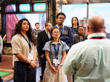 Group of UM students looking at an ESPN employee giving a tour of a recording studio.